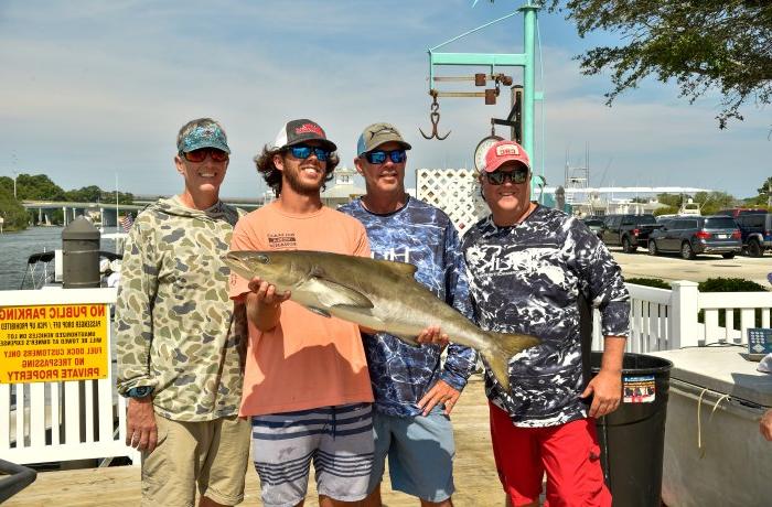 Group of men holding a cobia fish